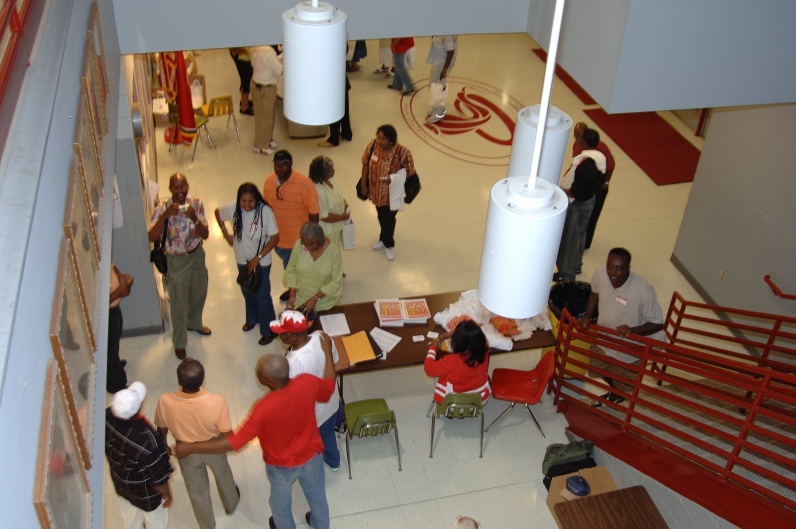 Overhead view of school gymnasium with people gathered, red and white floor markings