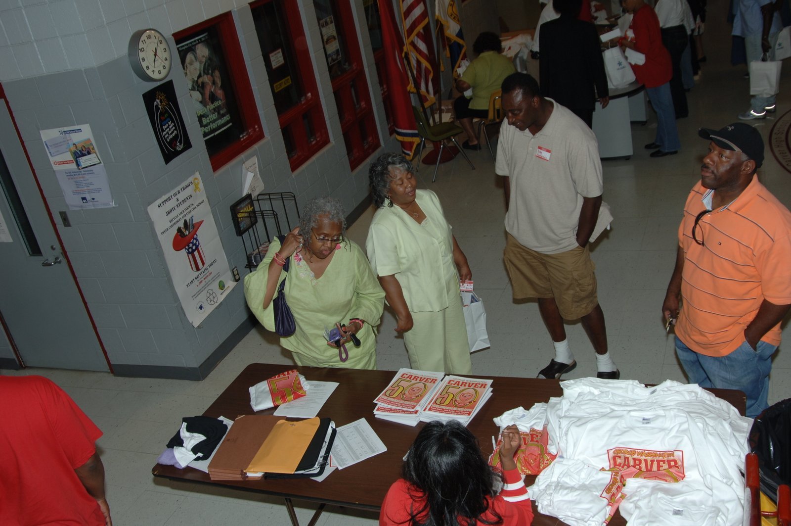 People at table with materials and merchandise, school event setup